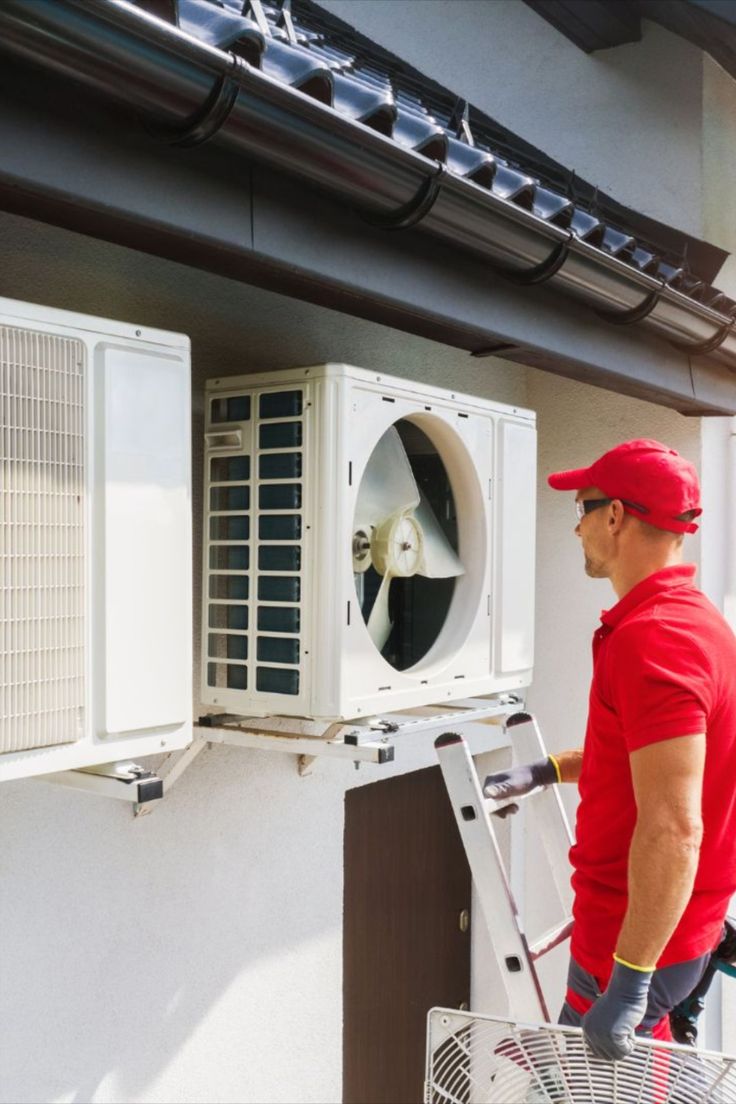 Technician installing and inspecting a modern wall-mounted air conditioning unit