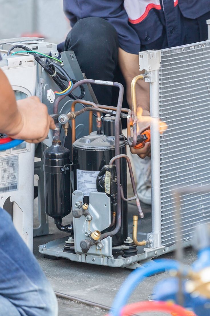 Technicians repairing internal air conditioner components and refrigerant lines